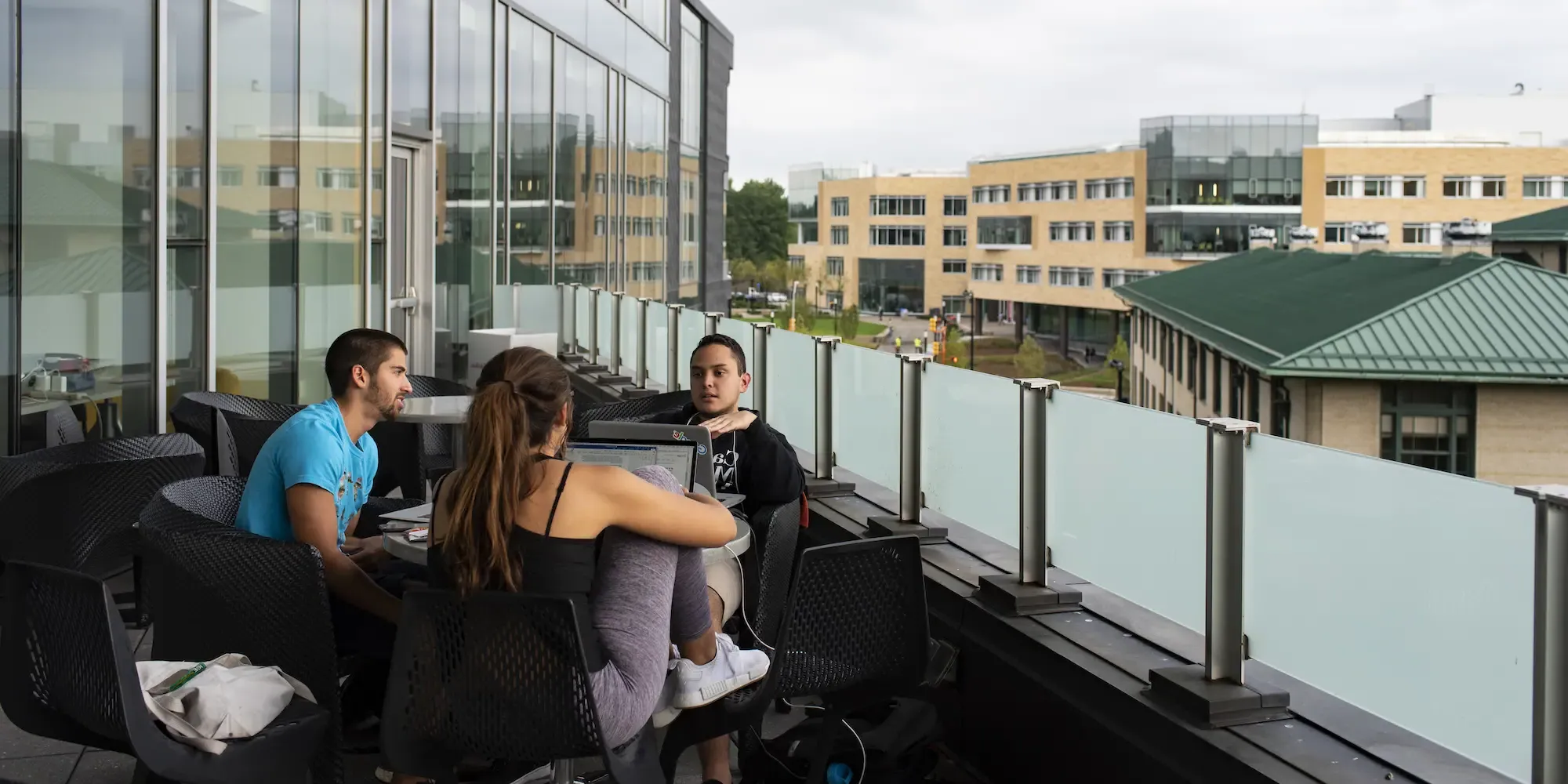 Students sitting on the balcony of the Tepper Quad, working from laptops.